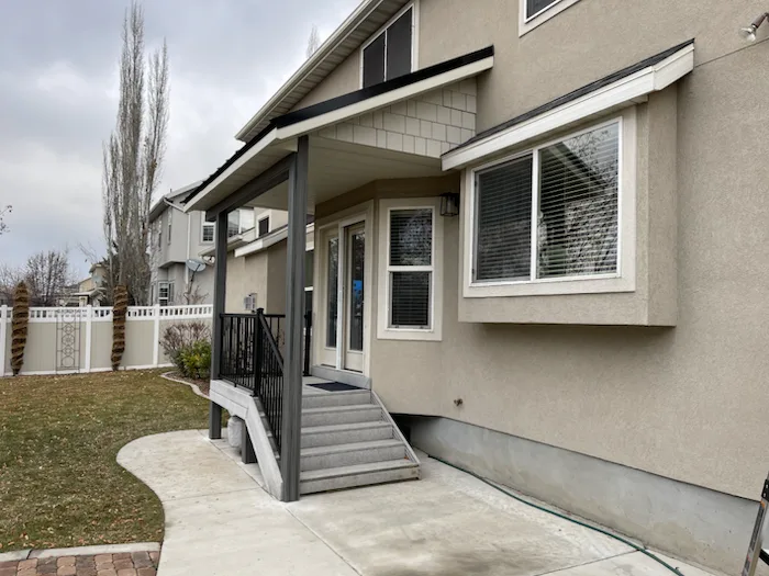 Custom home exterior with covered entry and fresh concrete walkway